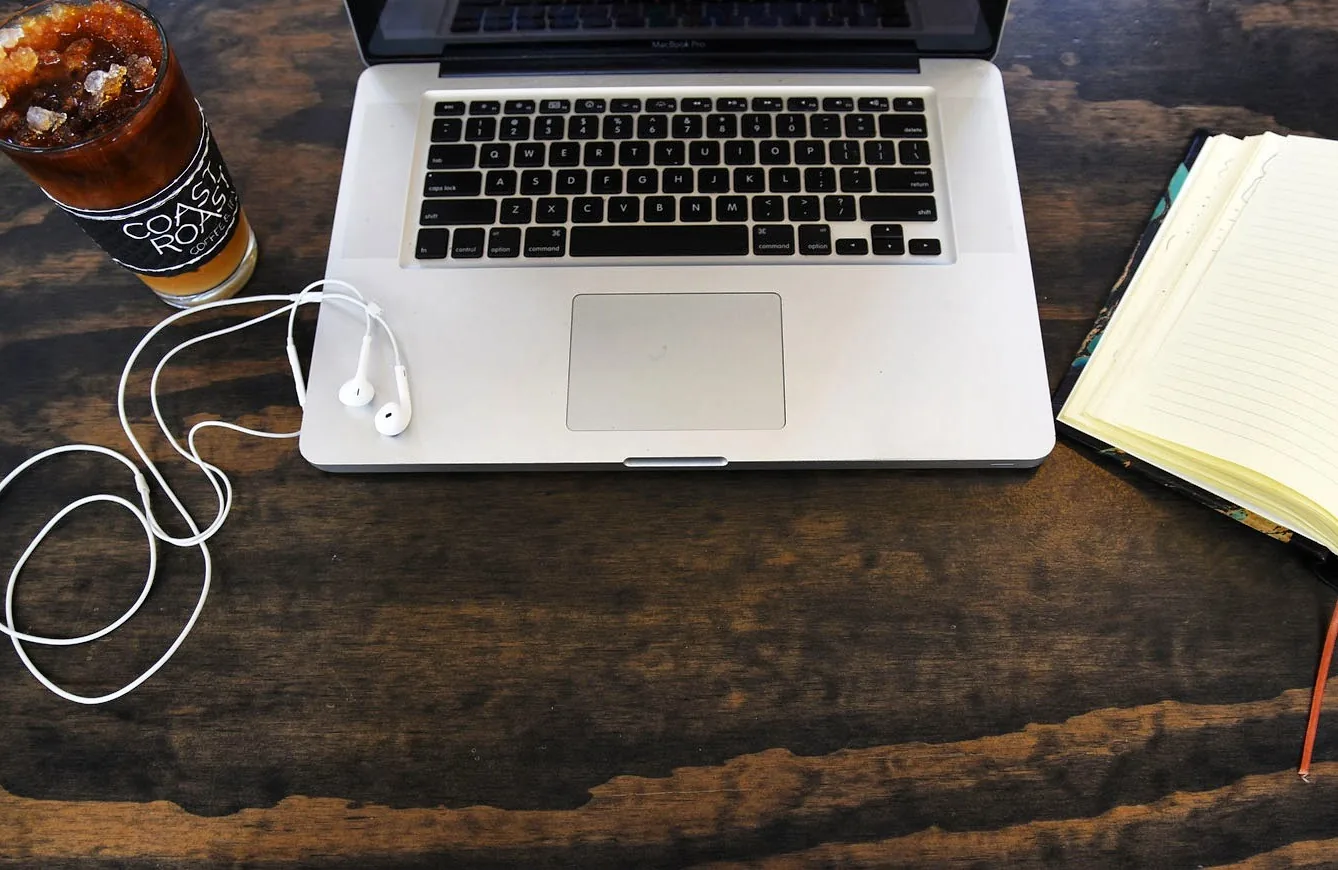 Laptop and Coast Roast iced coffee on a dark wood table at St. Roch Market