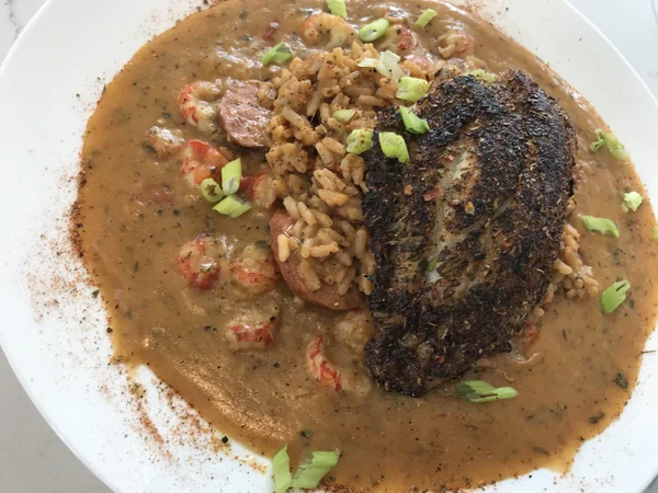 Blackened Catfish Louisiana at Chef Charles Bistreaux: a blackened catfish fillet over jambalaya, topped with crawfish étouffée and green onions