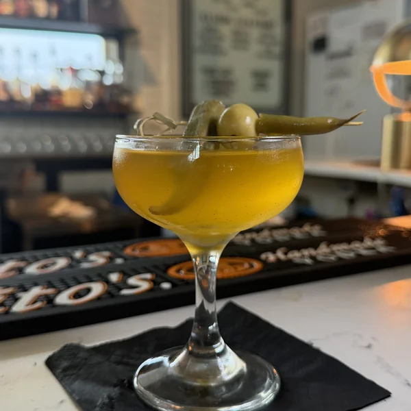 The golden Cajun Dirty Martini at Roch's Reprieve garnished with pickled okra and an olive