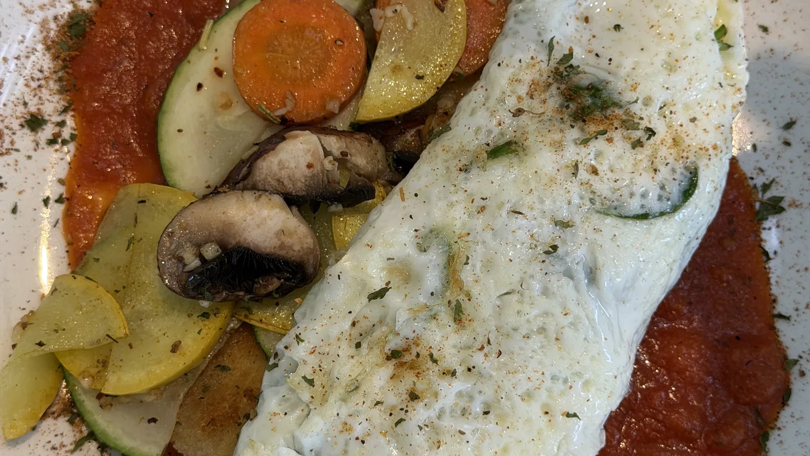 The vegetarian omelette at Chef Charles Bistreaux: an egg-white omelette folded over zucchini, squash, mushrooms, and spinach on a bed of red tomato sauce, served at St. Roch Market