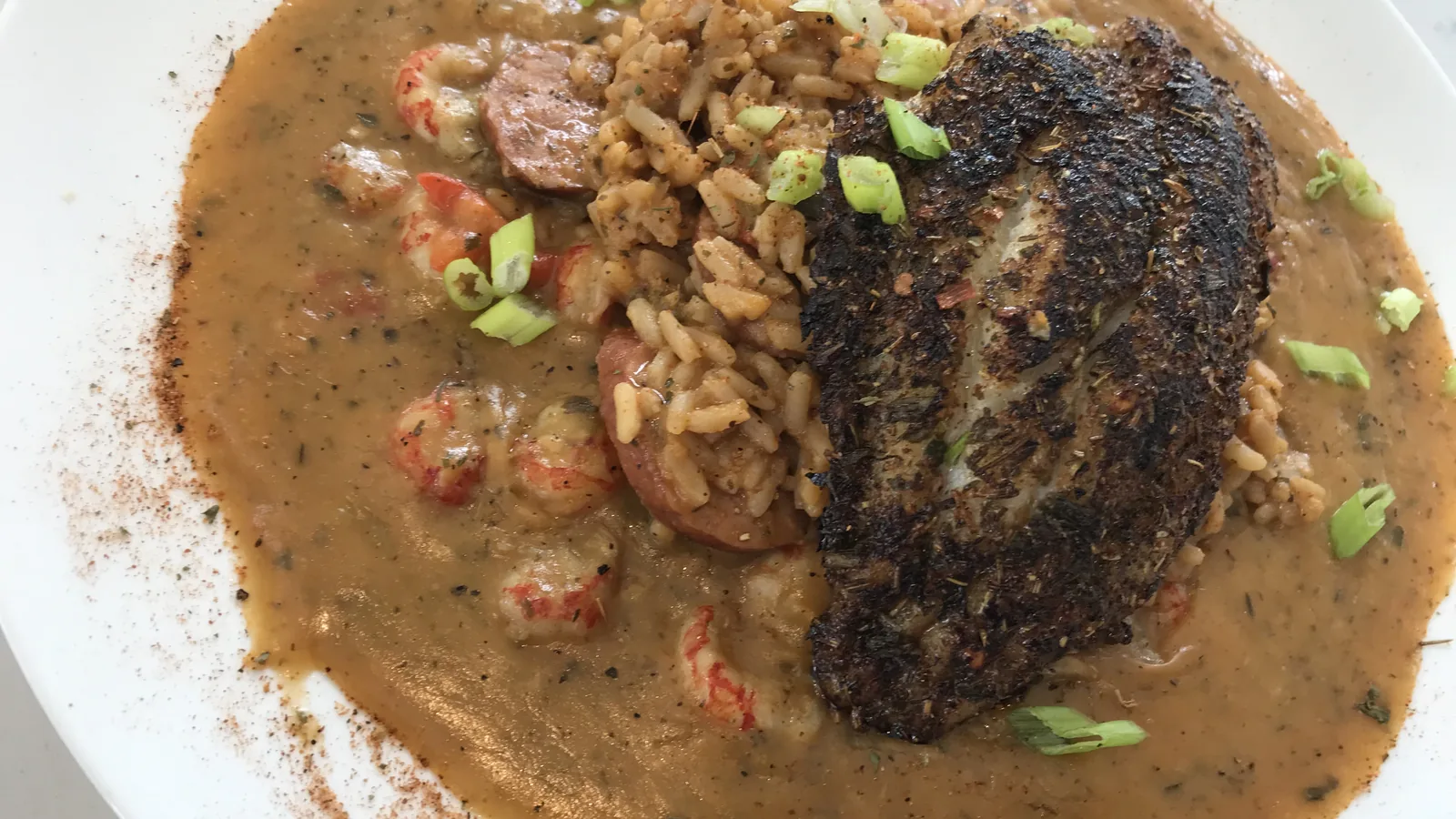 Blackened Catfish Louisiana at Chef Charles Bistreaux: a blackened catfish fillet over jambalaya, topped with crawfish étouffée and green onions