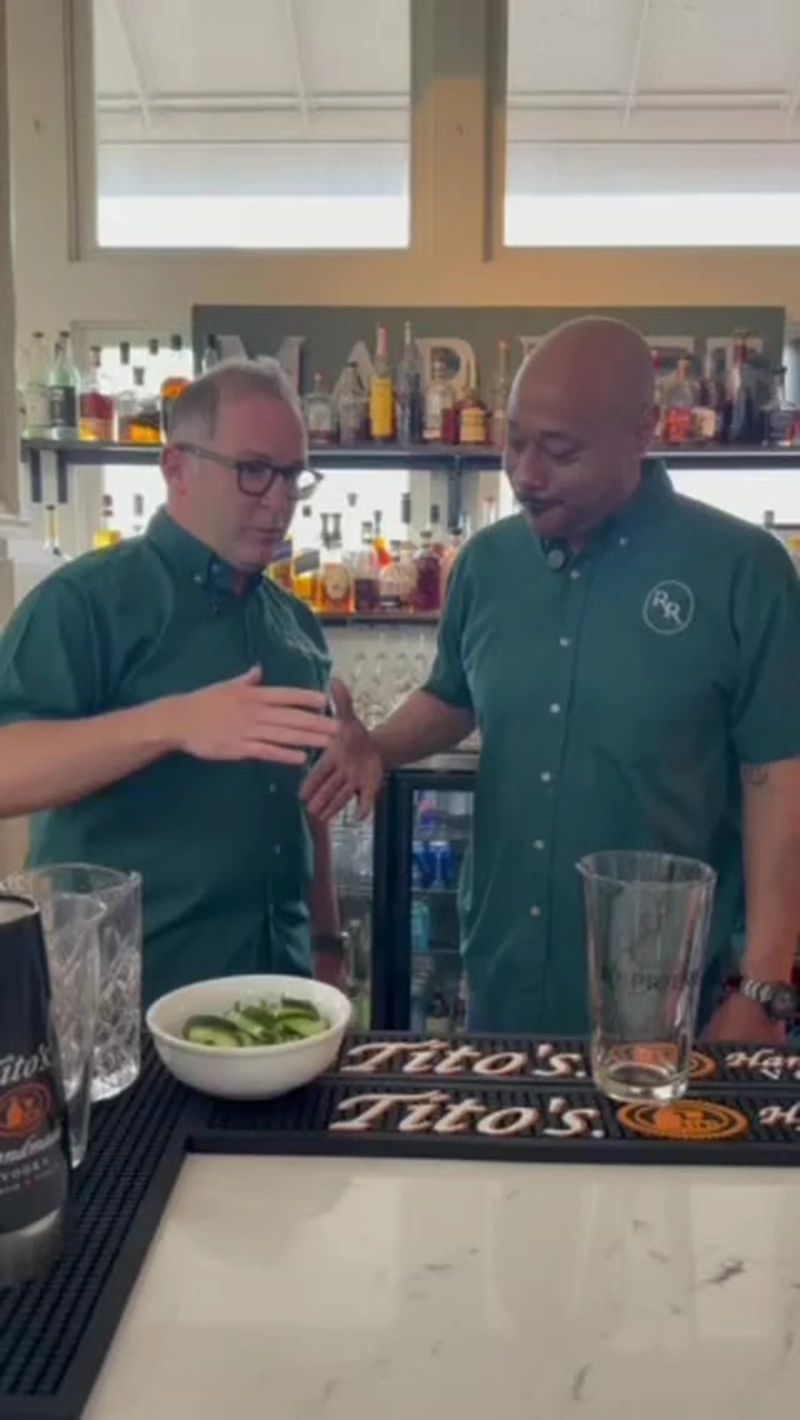 Sean Verrett and Kevin Pedeaux at the Roch's Reprieve bar with cucumbers, pint glasses, and Tito's bar mats ready for the Shoreline cocktail