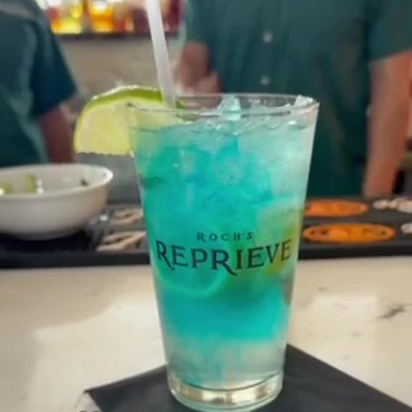 The Shoreline cocktail at Roch's Reprieve, bright blue with a lime wedge
