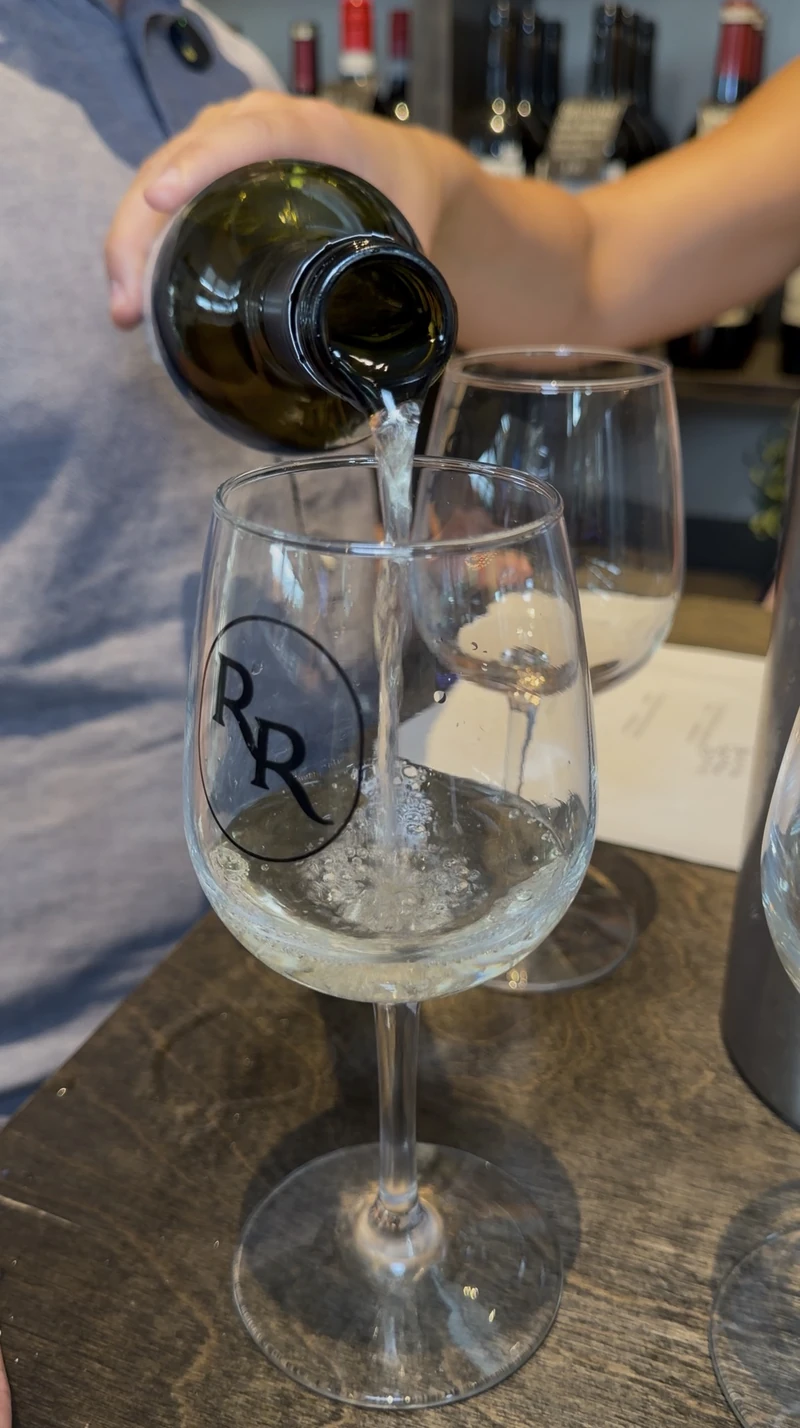 A white wine pour into a Roch's Reprieve logo wine glass at St. Roch Market