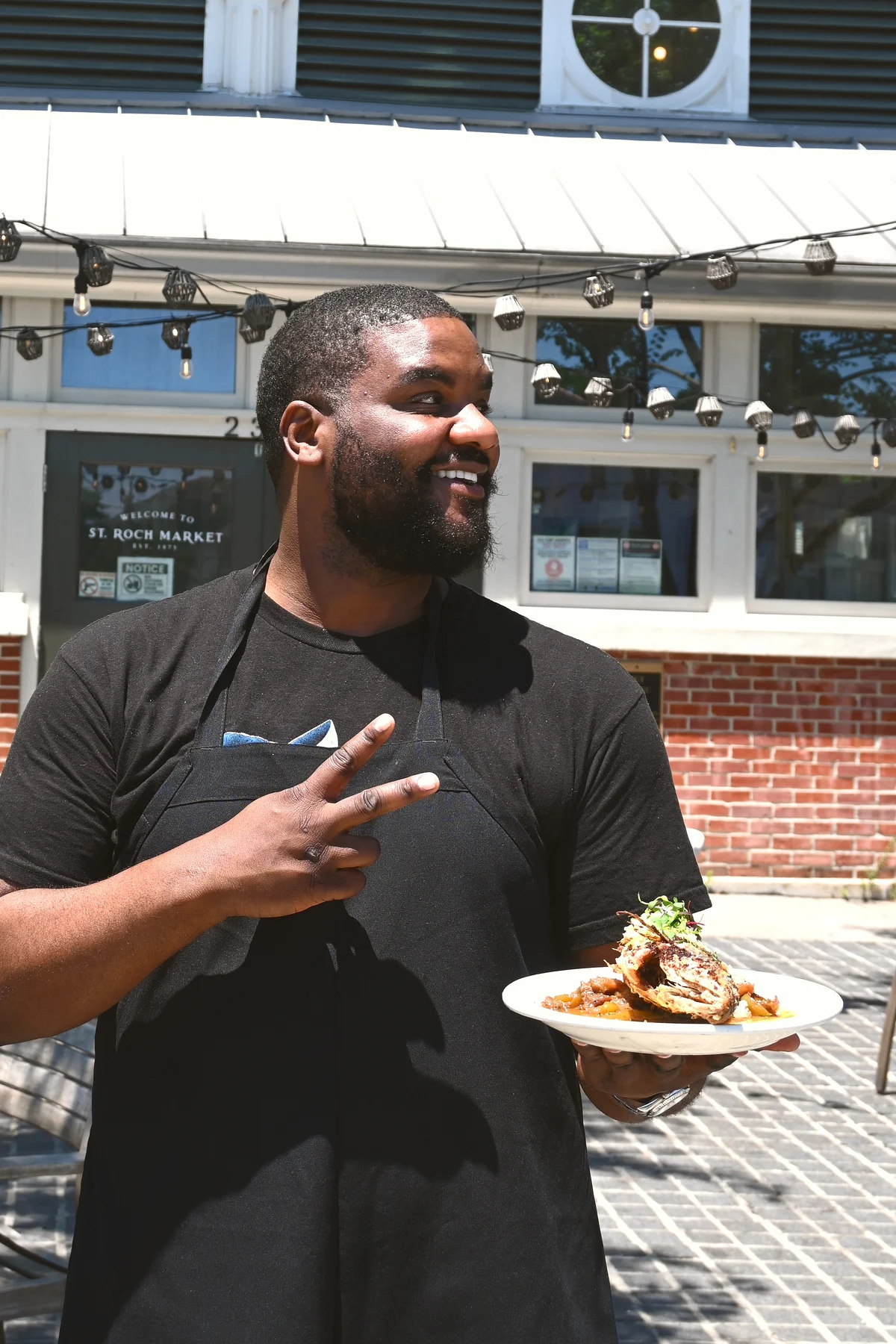 Chef Myron Hartford of Not Ya Maw Kitchen holding a plate at St. Roch Market New Orleans
